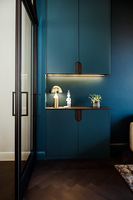 Een prachtige petrol kleurige maatwerkkast in de kleur van de wand. De kast bestaat uit twee gedeeltes, waar de grepen een ronde ovale vorm hebben, welke weer terugkomt in de separatie van de woning.